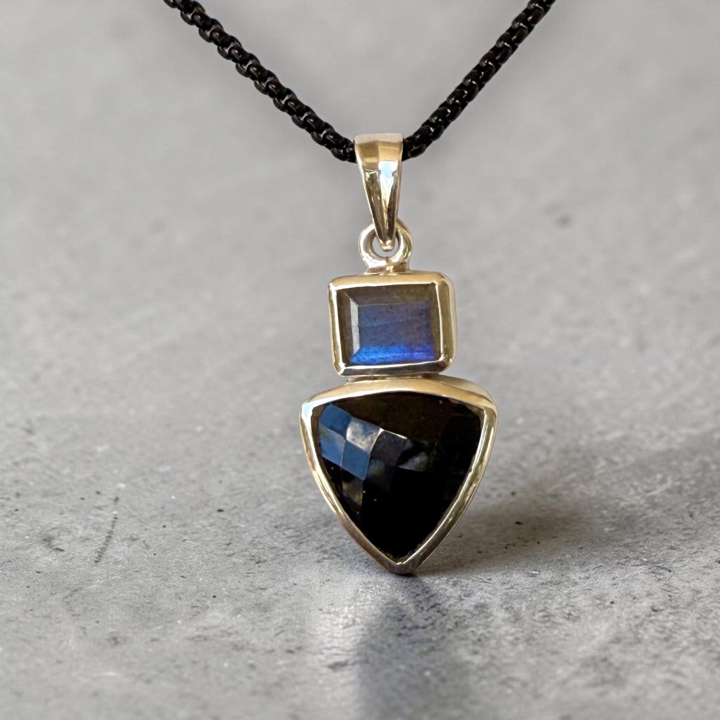 Black Mystic sterling silver pendant with labradorite and trillion-cut black spinel on a gray stone background